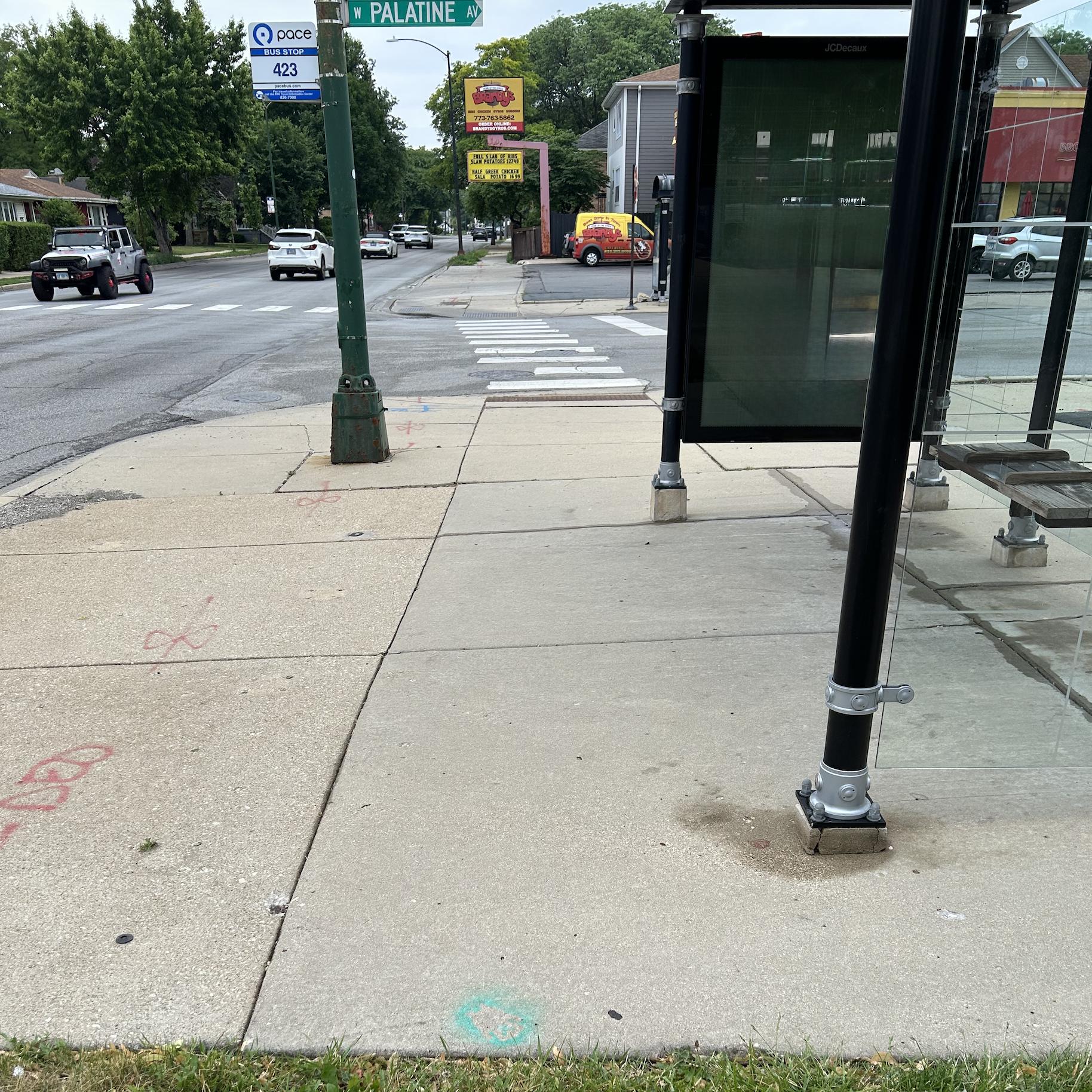 Photo of a green sidewalk bear far from curb ramp